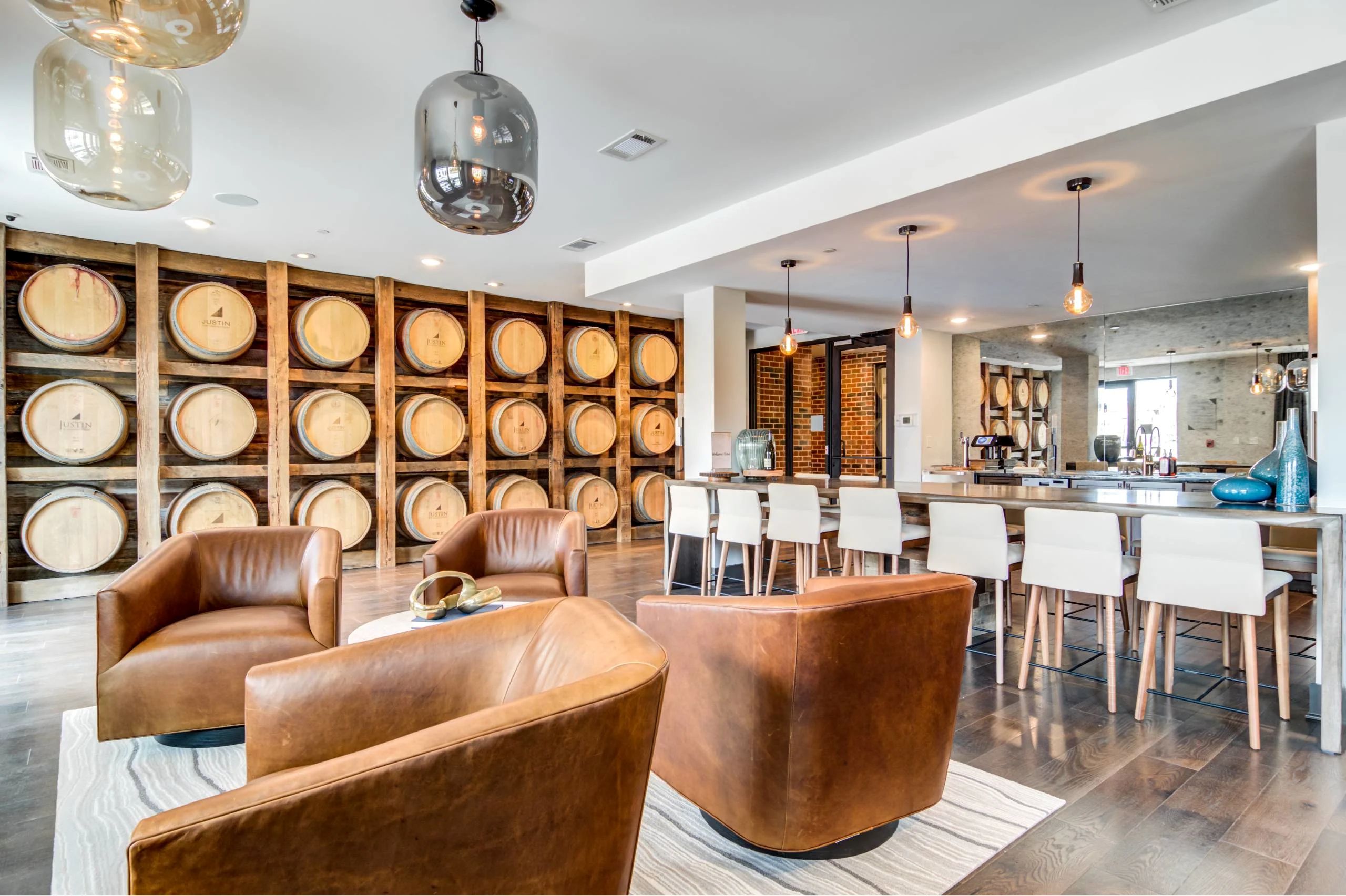 A resident lounge featuring a wall mounted with wine barrels, leather swivel armchairs, and high-top counter seating.